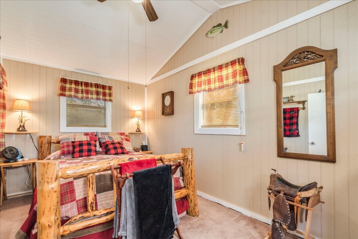 2411 Rohde Road Kyle, TX 78640 - Photo 23 of 40 Carpeted bedroom featuring lofted ceiling, wood walls, and ceiling fan