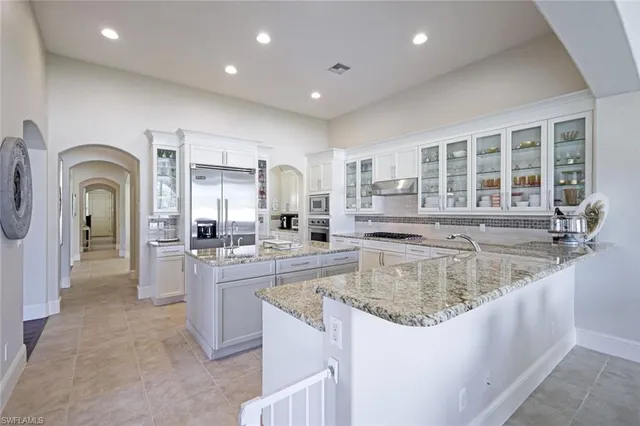 a large kitchen with kitchen island a large counter top stainless steel appliances and cabinets