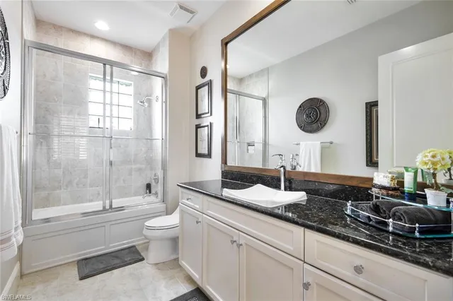 a bathroom with a granite countertop sink mirror vanity and toilet