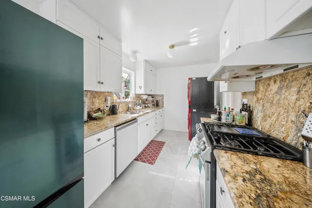 a kitchen with stainless steel appliances kitchen island granite countertop a refrigerator and a stove top oven