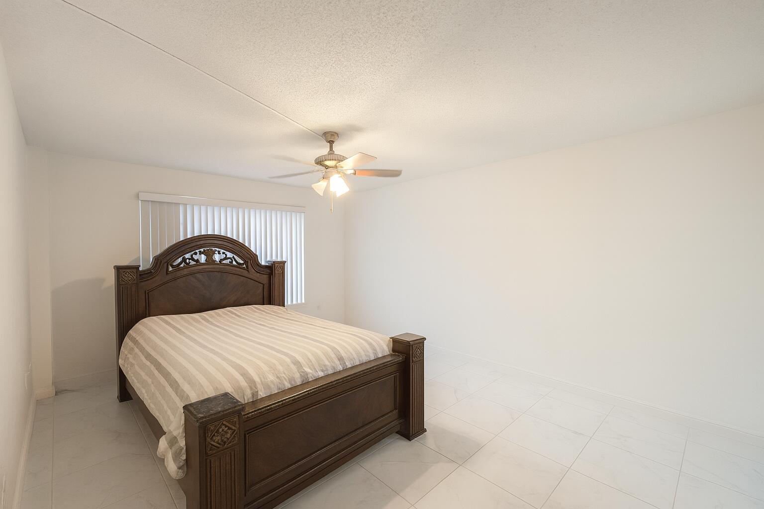 4174 Inverrary Drive, Unit 102 Lauderhill, FL 33319 - Photo 7 of 10 a bedroom with a bed and a lamp on dresser