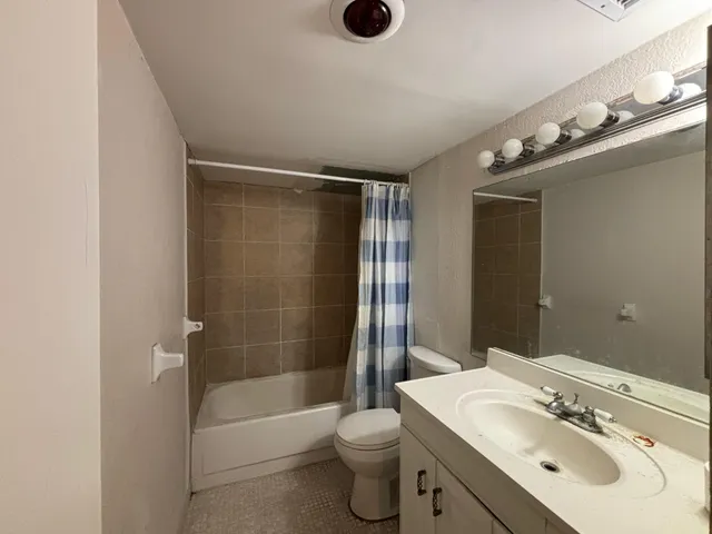 a bathroom with a bathtub shower sink vanity mirror and toilet