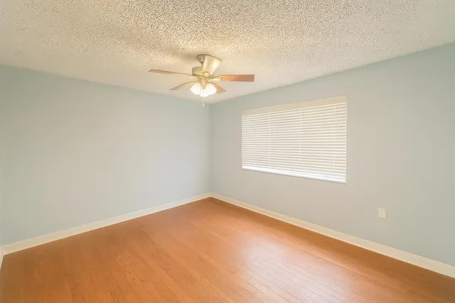 an empty room with a window and a ceiling fan