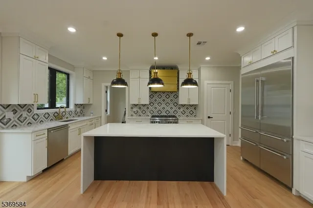 a kitchen with stainless steel appliances granite countertop a sink a stove and a refrigerator