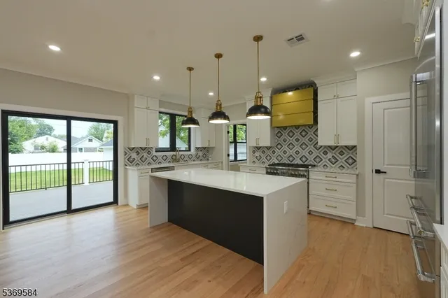 a large kitchen with kitchen island a large counter top space a sink stainless steel appliances and cabinets