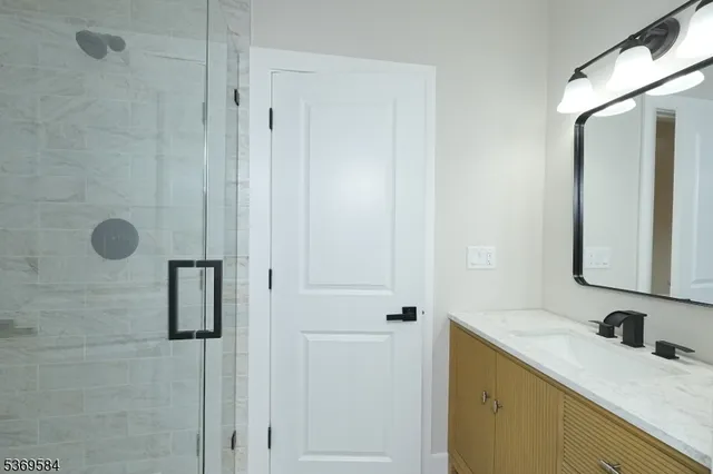 a bathroom with a granite countertop sink a mirror and shower