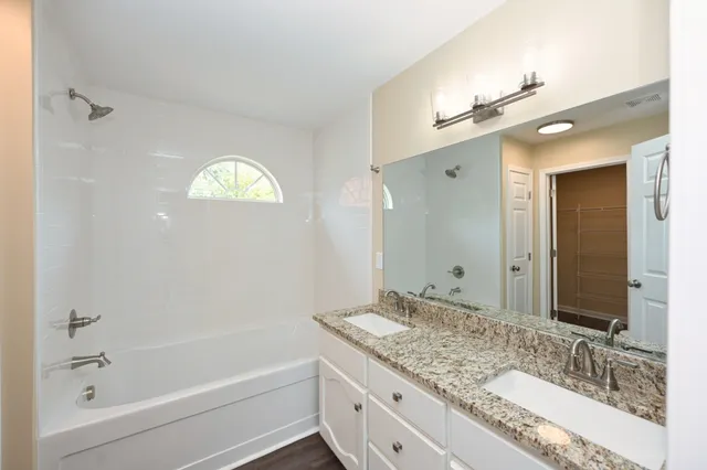 a bathroom with a granite countertop sink a large mirror and shower