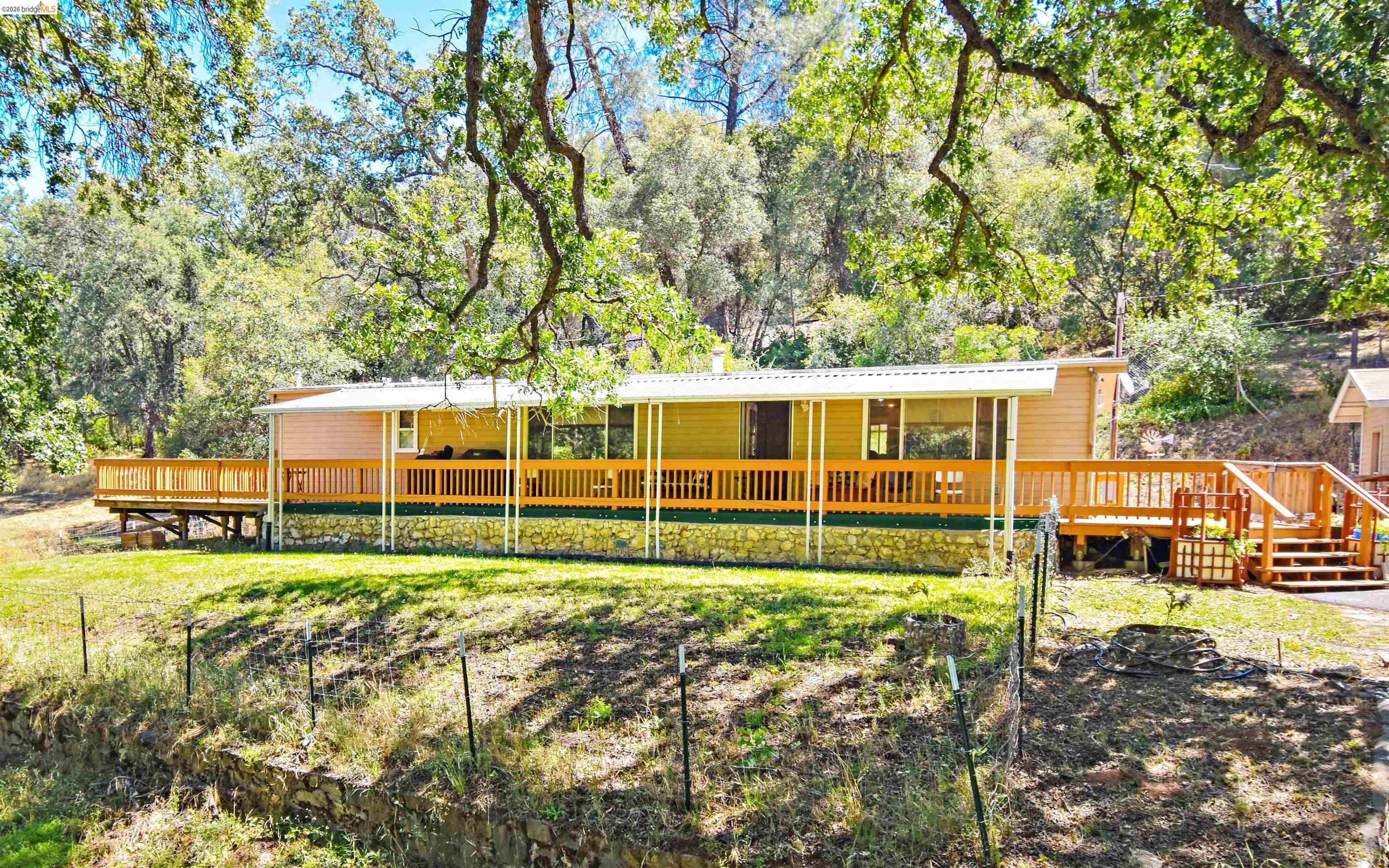 13904 Tuolumne Road Sonora, CA 95370 - Photo 38 of 44 Single-story residence featuring a full-length covered porch, an expansive wood deck, and a multi-tiered wood staircase entrance