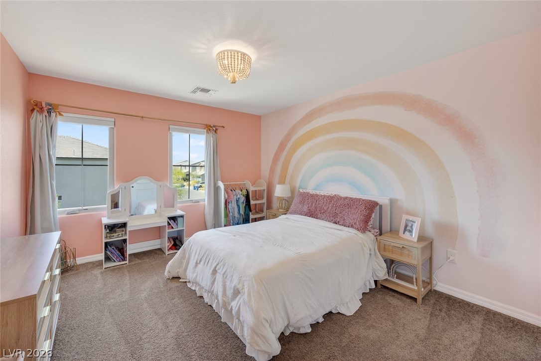 10446 Emerald Rye Street Las Vegas, NV 89183 - Photo 27 of 37 A cheerful bedroom with warm-toned walls features a decorative chandelier and inviting neutral carpet.