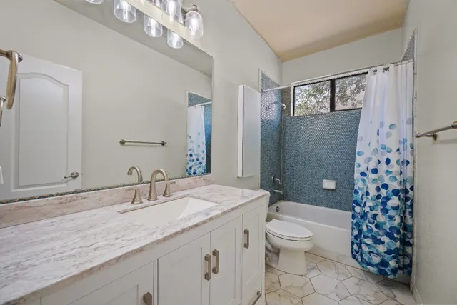 a bathroom with a granite countertop sink a toilet a mirror a vanity and shower