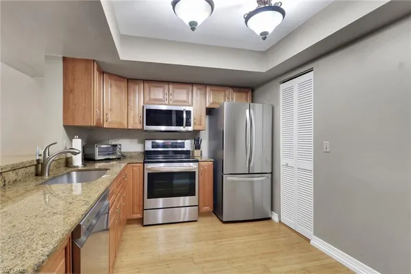 a kitchen with stainless steel appliances granite countertop a refrigerator a stove a sink and a microwave