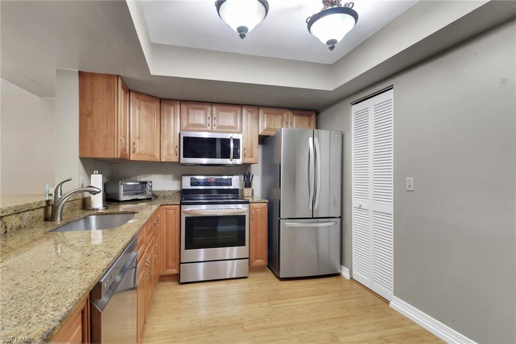 800 Meadowland Drive, Unit 252 Naples, FL 34108 - Photo 5 of 21 a kitchen with stainless steel appliances granite countertop a refrigerator a stove a sink and a microwave