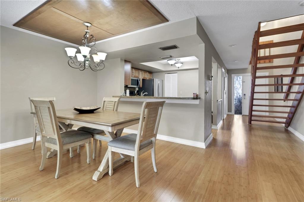 800 Meadowland Drive, Unit 252 Naples, FL 34108 - Photo 7 of 21 a view of a dining room with furniture wooden floor and chandelier