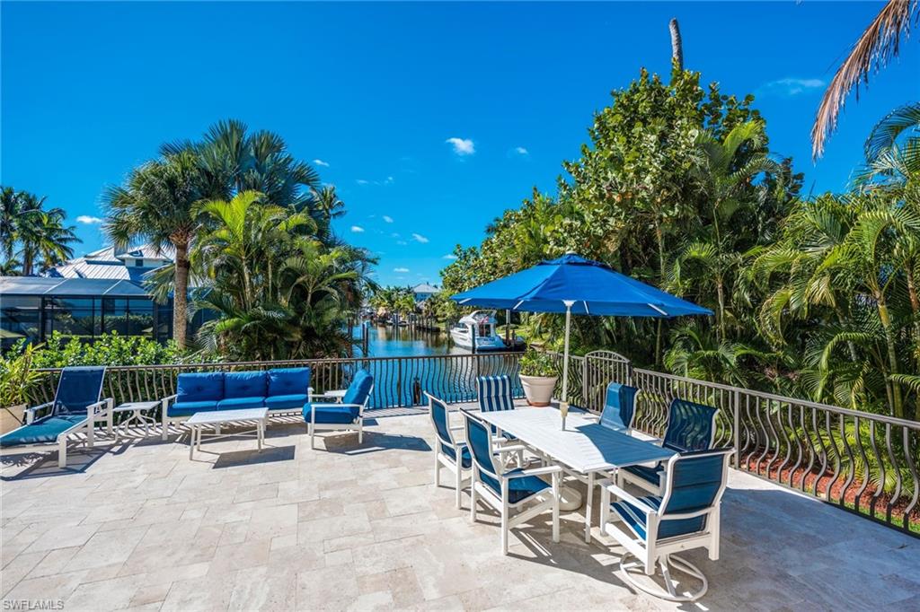 1672 Jewel Naples, FL 34102 - Photo 19 of 27 a roof deck with table and chairs under an umbrella with potted plants