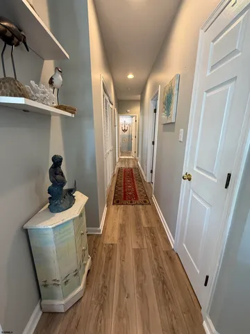 a view of a hallway to a livingroom with wooden floor and staircase