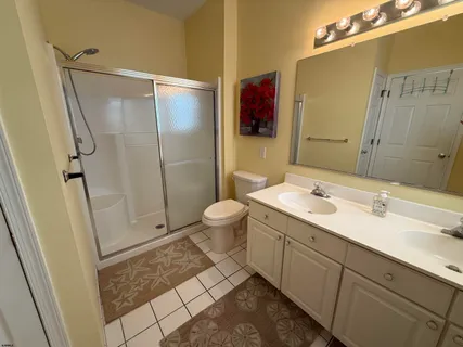 a spacious bathroom with a double vanity sink toilet mirror and shower