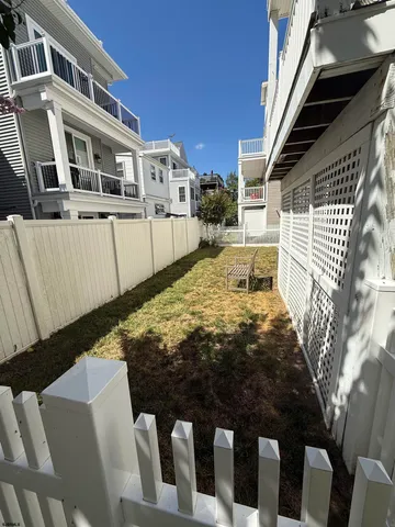 a backyard of a house with large trees and wooden fence