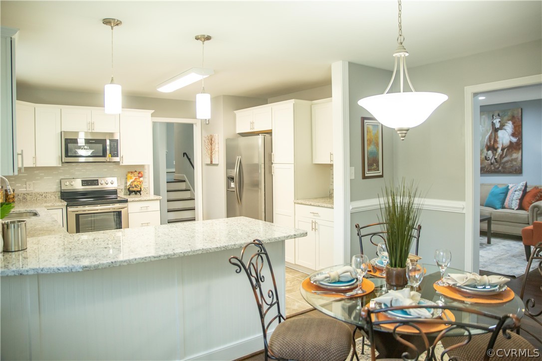 8530 Cherokee Road Richmond, VA 23235 - Photo 6 of 40 a kitchen with stainless steel appliances kitchen island granite countertop a table and chairs in it