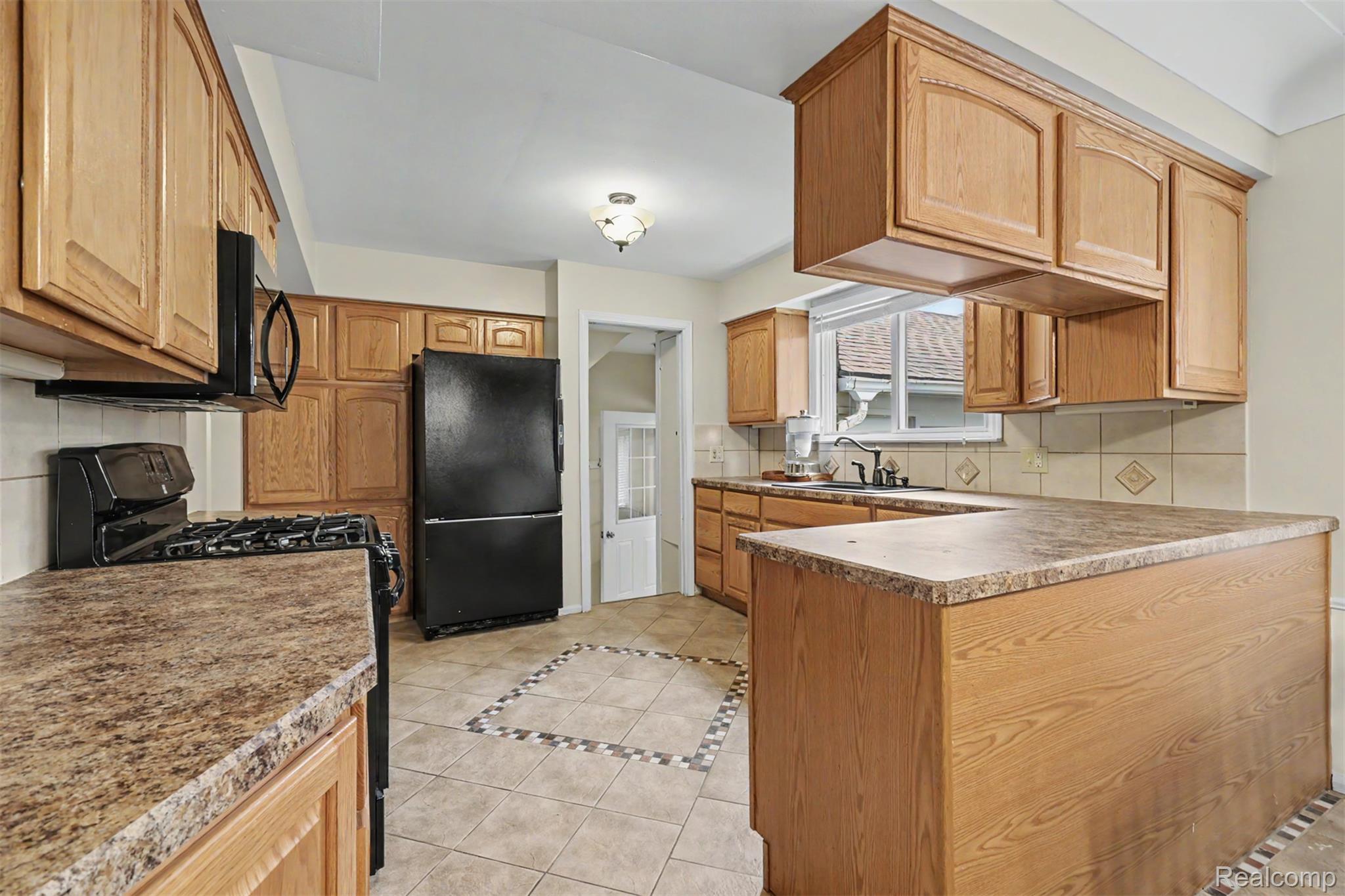 7136 Rosedale Boulevard Allen Park, MI 48101 - Photo 15 of 51 Kitchen featuring wood cabinetry, speckled countertops, tile flooring with decorative accents, and a black appliance suite