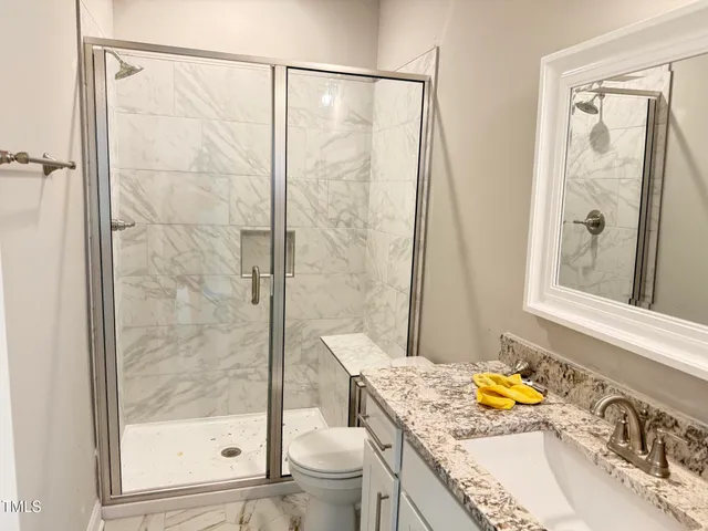 a bathroom with a granite countertop sink a toilet and shower