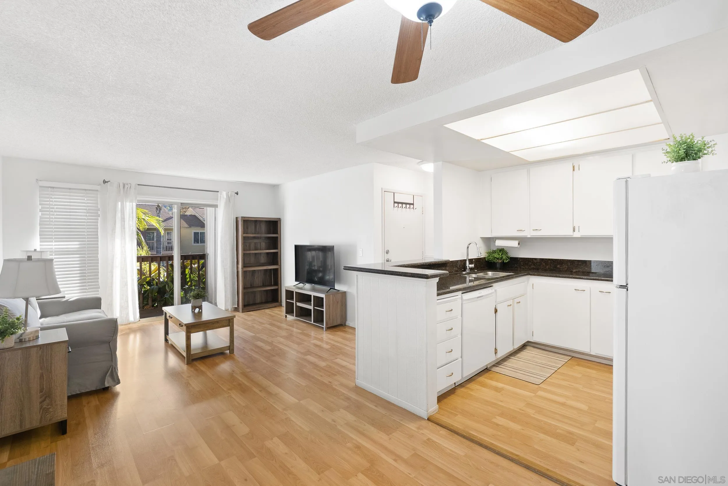 5978 Rancho Mission Road, Unit 274 San Diego, CA 92108 - Photo 3 of 23 a kitchen with white cabinets and wooden floor