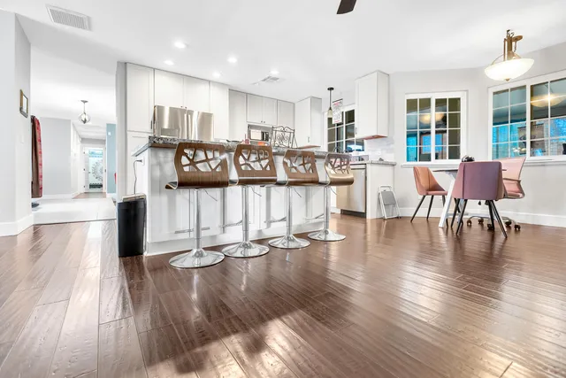 a living room with lots of furniture wooden floor and a large window
