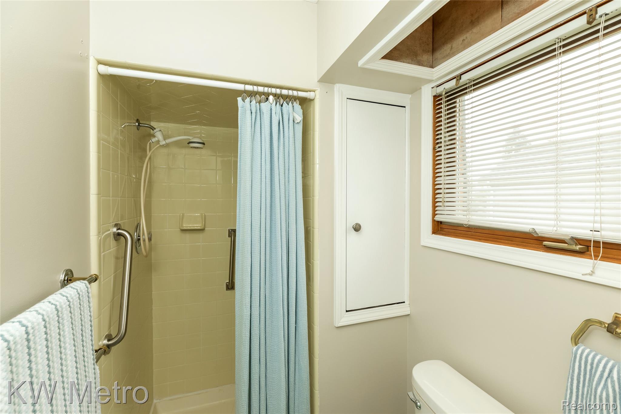 2154 Warrington Road Rochester, MI 48307 - Photo 20 of 41 Tiled shower stall with a grab bar, featuring an adjustable showerhead and a built-in soap dish