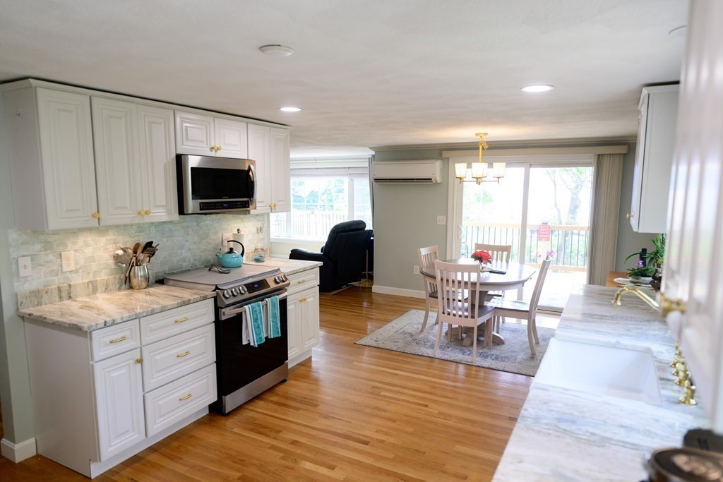 462 Goldthwaite Road Northbridge, MA 01588 - Photo 17 of 40 a kitchen with stainless steel appliances granite countertop a stove top oven a sink a dining table and chairs with wooden floor