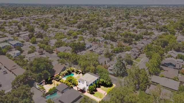 an aerial view of residential houses with outdoor space and trees all around