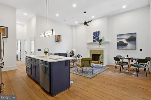a kitchen with stainless steel appliances granite countertop wooden floors and a view of living room