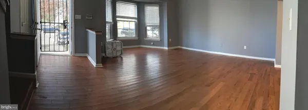 a view of a room with wooden floor and a kitchen
