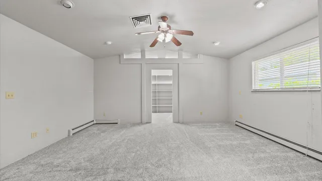 an empty room with a ceiling fan and a window