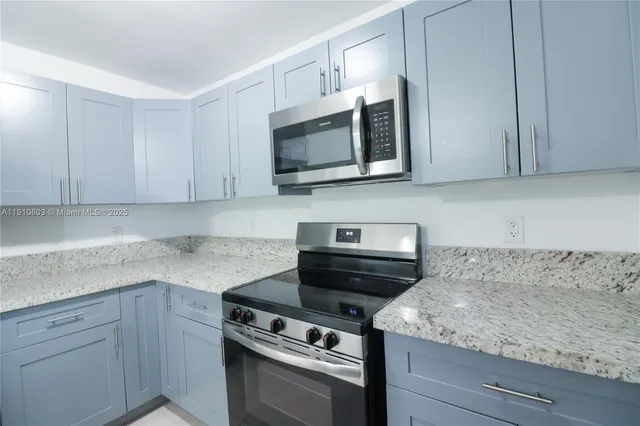 a kitchen with stainless steel appliances granite countertop white cabinets and a stove