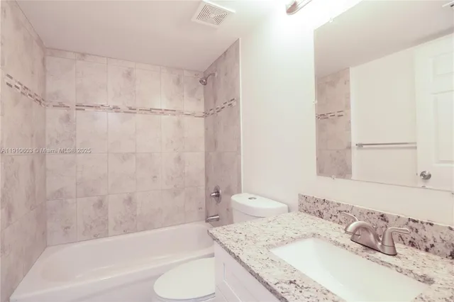 a bathroom with a granite countertop sink and a bathtub