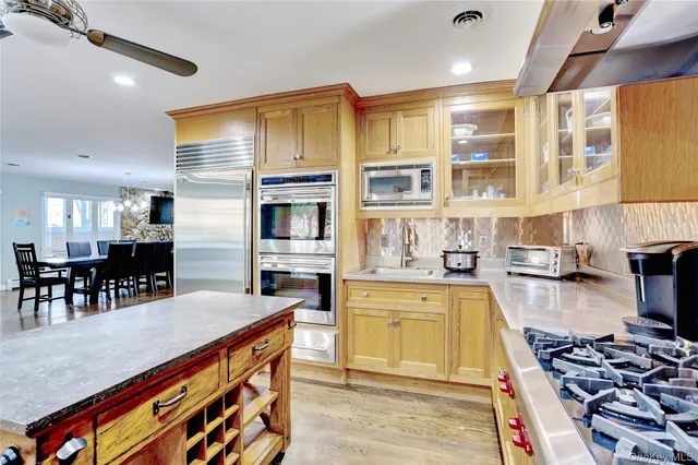 a kitchen with stainless steel appliances granite countertop a stove and a view of living room