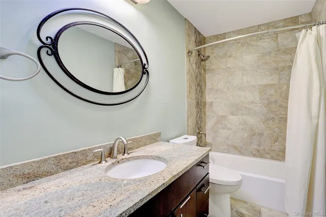 a bathroom with a granite countertop sink toilet and a mirror