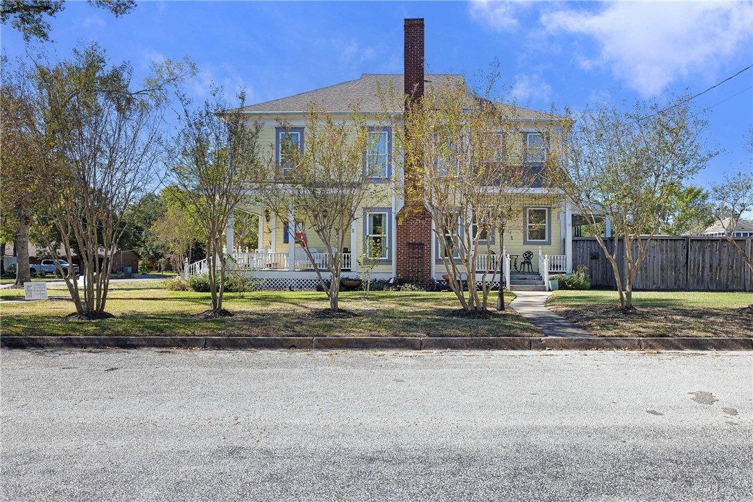 a view of a big house with a yard and large tree