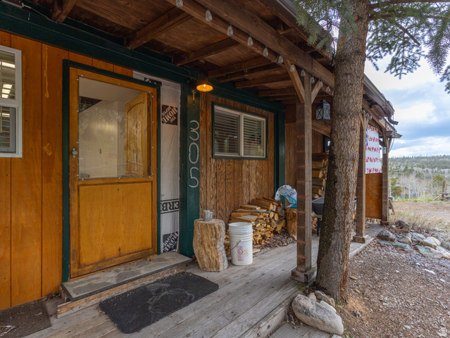 5082 Pine Crest Road Evanston, UT 82930 - Photo 5 of 25 Rustic wood siding with a covered porch featuring exposed wood beams, a wood plank ceiling, and a prominent tree integrated into the porch structure