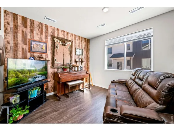 a living room with furniture a flat screen tv and wooden floor