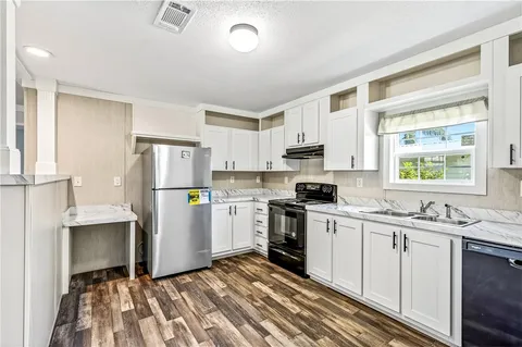 a kitchen with a sink appliances cabinets and a window
