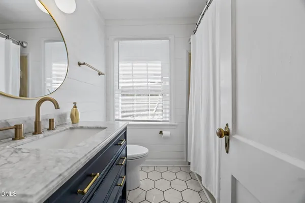 a bathroom with a granite countertop sink a toilet and a mirror