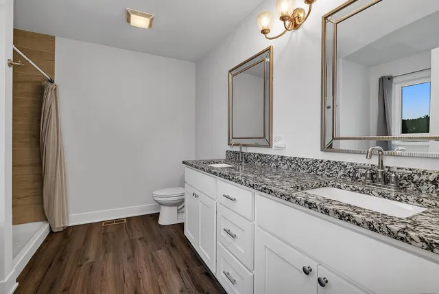 a bathroom with a granite countertop sink toilet and mirror