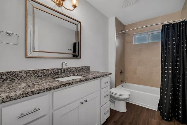 a bathroom with a granite countertop toilet a sink and a bathtub