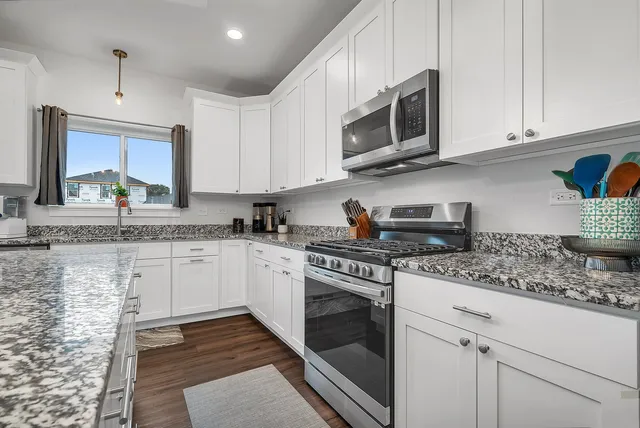 a kitchen with stainless steel appliances granite countertop a stove a sink and a microwave