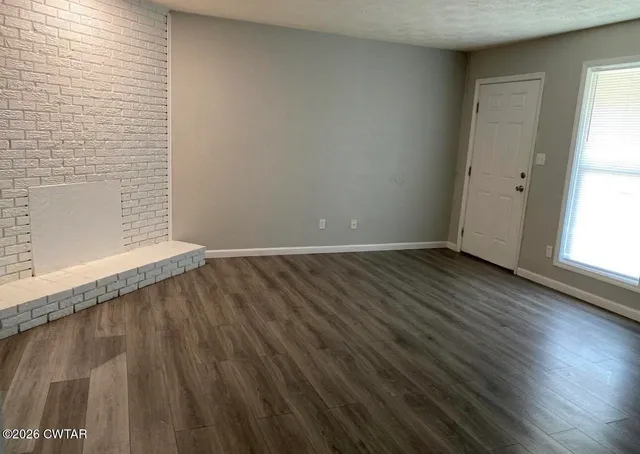 an empty room with wooden floor and window