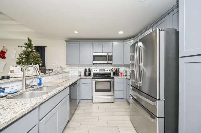 a kitchen with stainless steel appliances granite countertop a sink refrigerator and cabinets