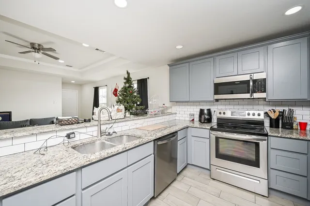 a kitchen with granite countertop a sink stainless steel appliances and white cabinets