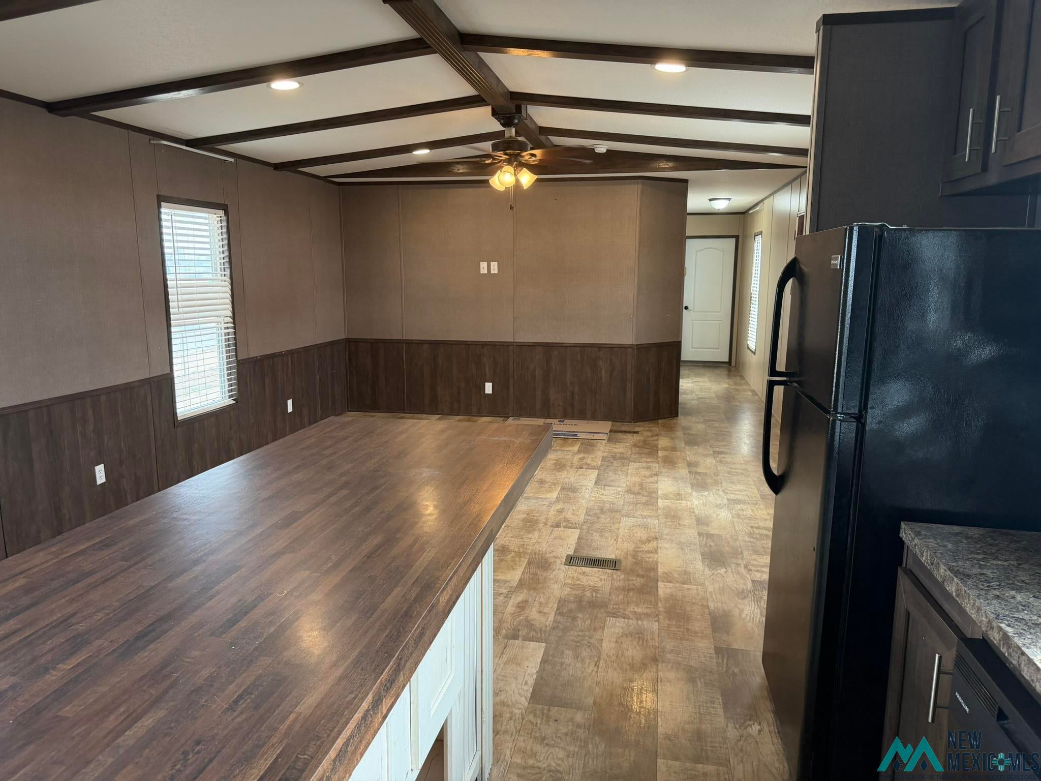 801 Riata Road Carlsbad, NM 88220 - Photo 9 of 39 Open concept living area featuring wood-finish flooring, accent wainscoting, and exposed beam ceiling details