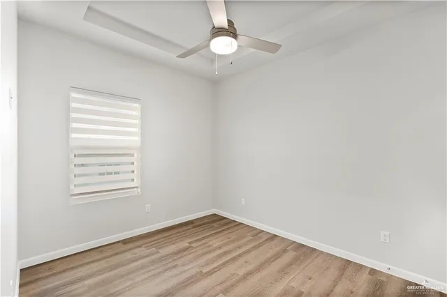 an empty room with wooden floor closet and windows