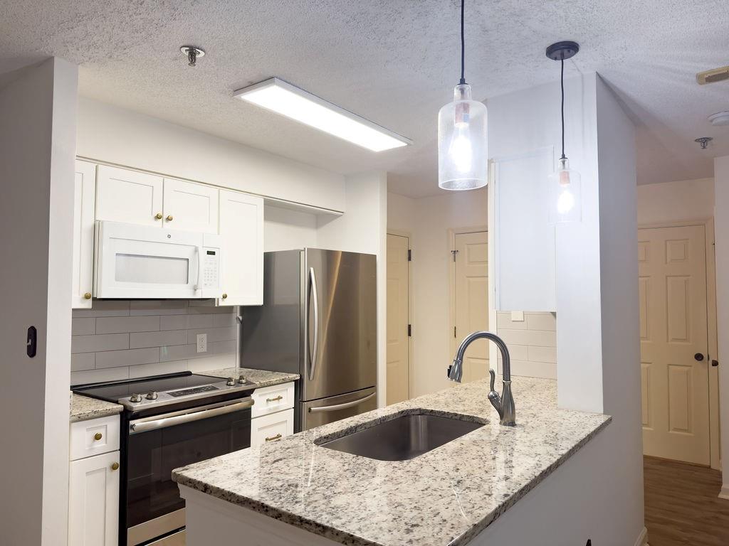 300 Johnson Ferry Road, Unit A305 Atlanta, GA 30328 - Photo 11 of 27 a kitchen with refrigerator a stove a sink and white cabinets